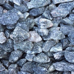 A close-up of numerous gray and white stones, showing varied textures and sizes, filling the entire frame with natural, rugged detail.