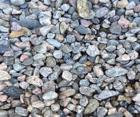 The image shows a collection of variously colored small pebbles and stones closely packed together, creating a textured and natural background pattern.