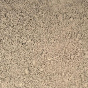 Close-up view of fine, textured sand with small pebbles scattered across its surface, creating a natural, earthy pattern. No landmarks or people.