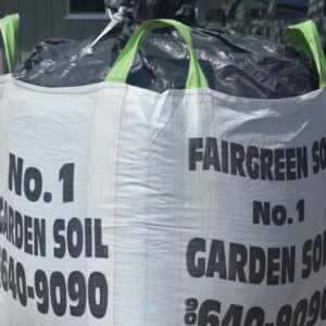 Large bag of "No. 1 garden soil" with green handles and black lettering. It is outdoors on a sunny day.