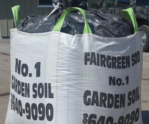 Large bag of "No. 1 garden soil" with green handles and black lettering. It is outdoors on a sunny day.